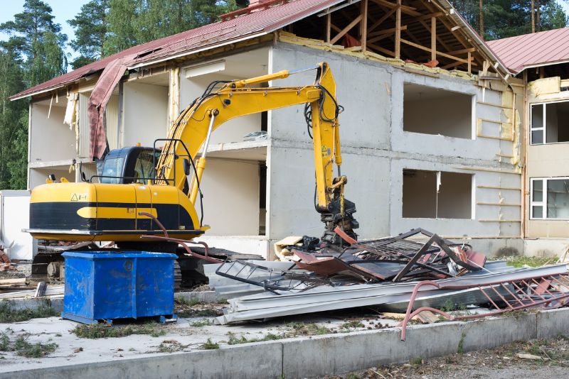 yellow excavator demolishing a house